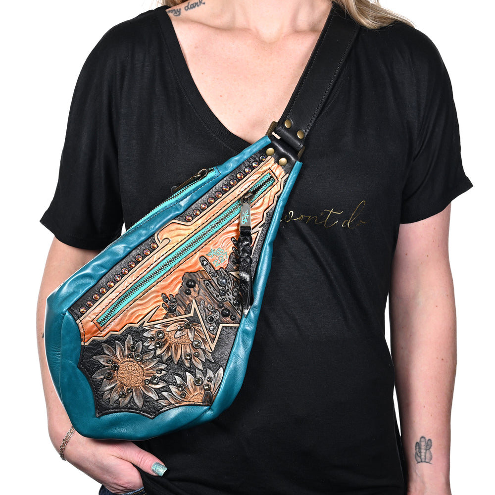 
                  
                    Woman wearing a black v-neck t-shirt showcasing a Heritage Brand fyra bag #227 with a turquoise and brown pattern.
                  
                