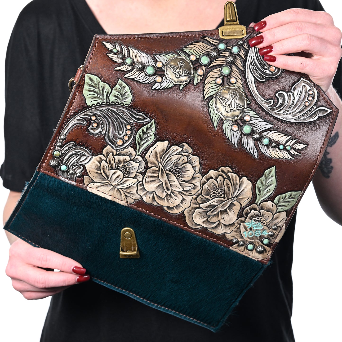 
                  
                    A person holding a Heritage Brand Nola Clutch #1084 with floral embossing and a contrasting green fur detail.
                  
                