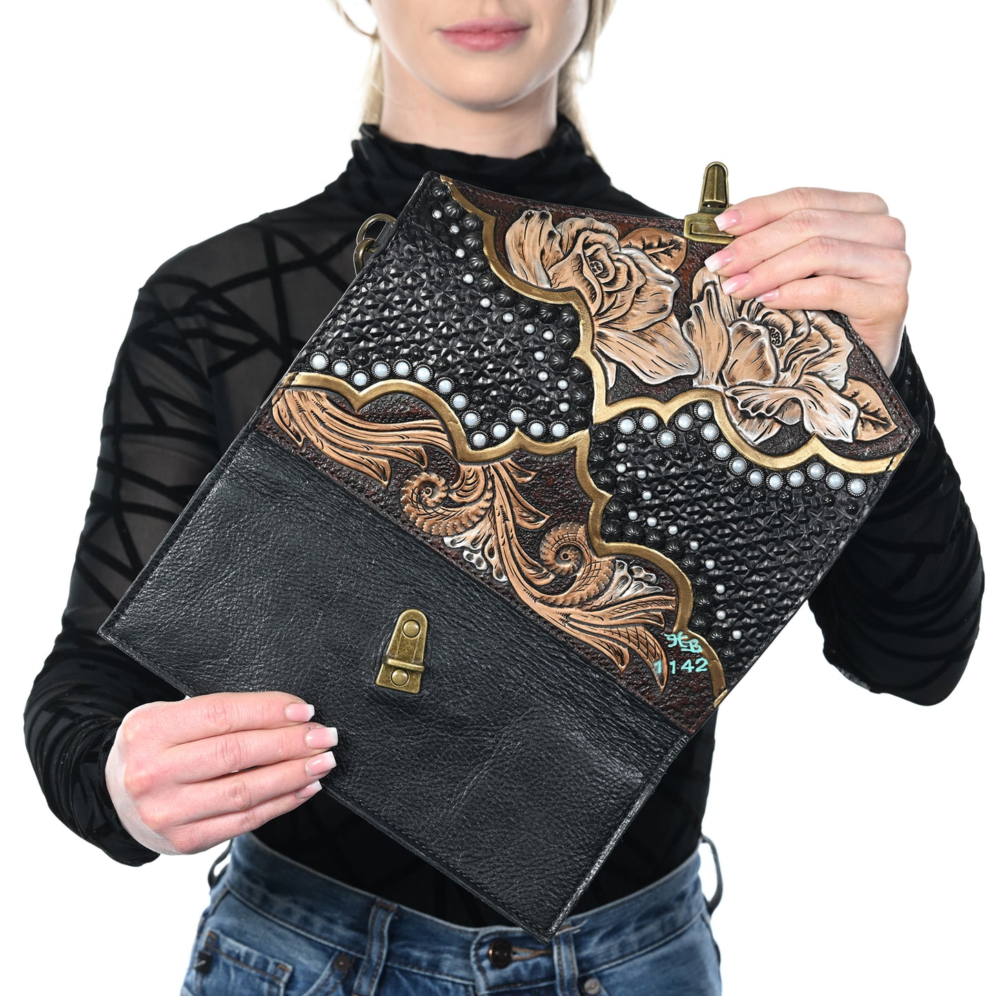 
                  
                    A person holding a decorated black nola clutch #1142 by Heritage Brand with floral and pearl accents.
                  
                