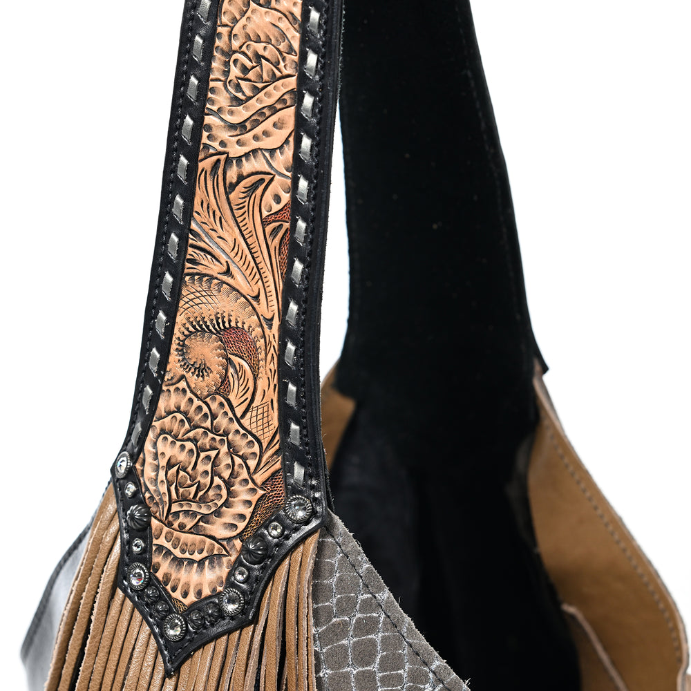 
                  
                    Close-up of a detailed Heritage Brand marilyn bag #5144 with embossed pattern and metal accents against a black and tan background.
                  
                