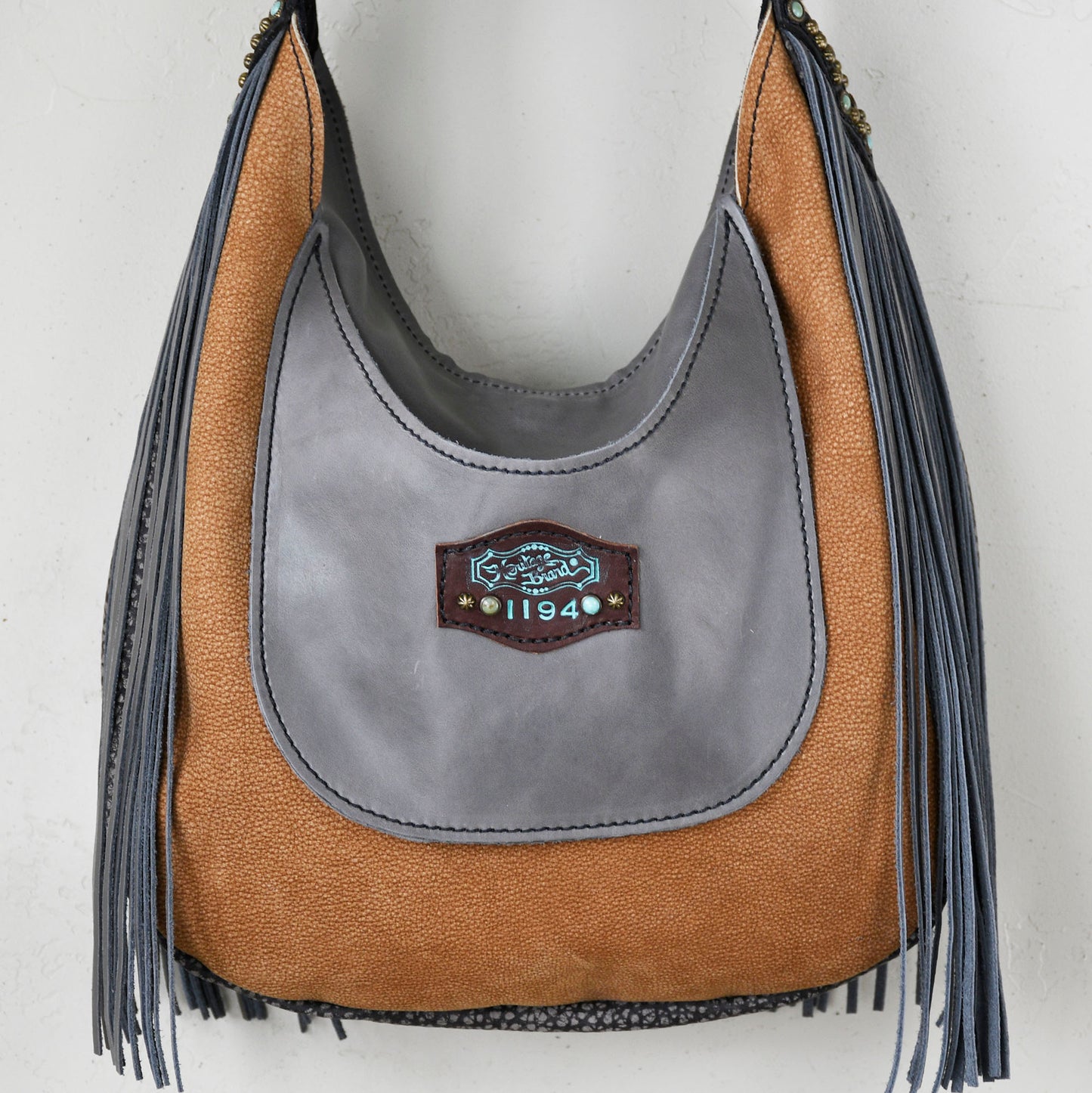 
                  
                    Gray and brown tasseled Heritage Brand Marilyn Bag against a white background.
                  
                