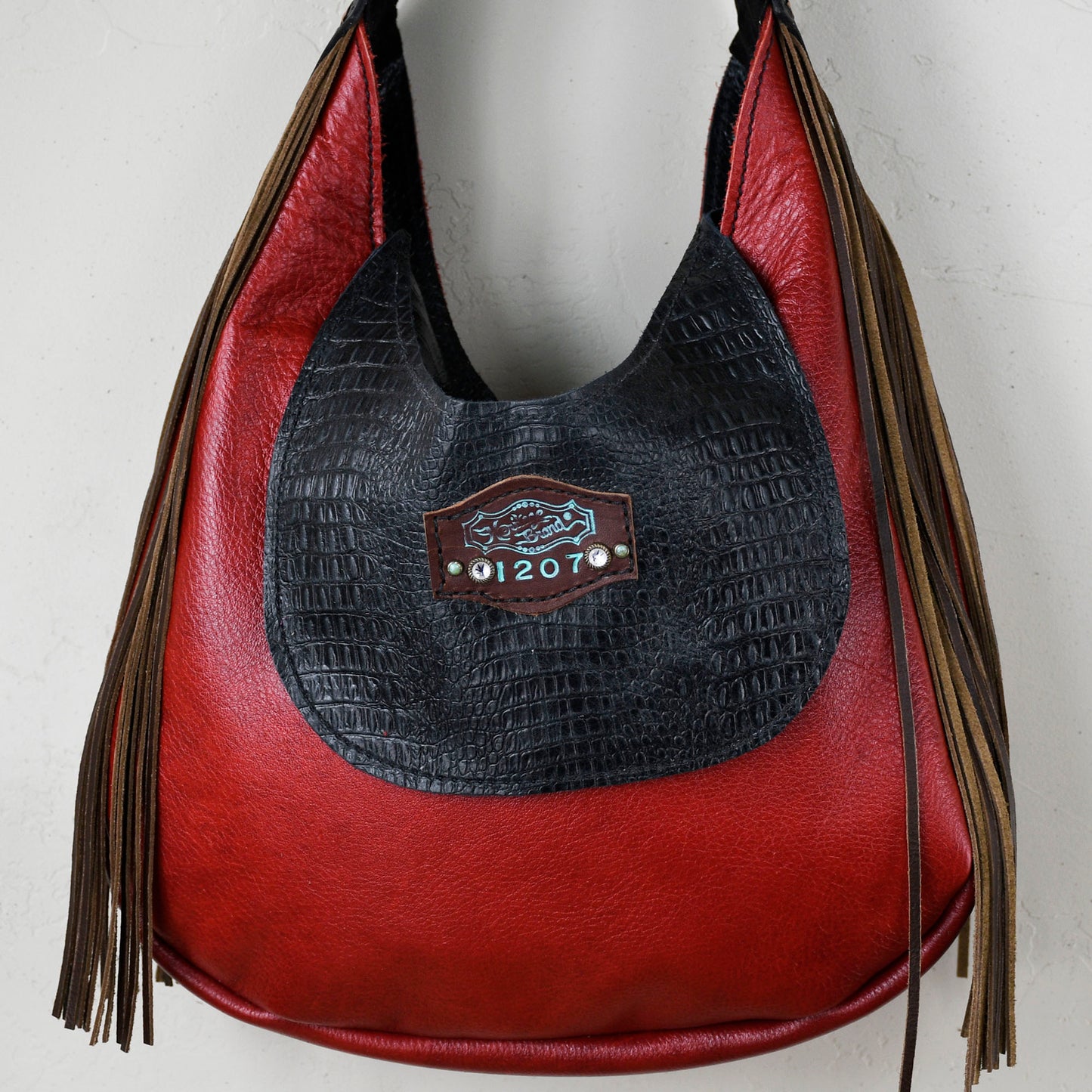 
                  
                    Black and red leather marilyn bag #11 with fringe and a metallic emblem by Heritage Brand.
                  
                