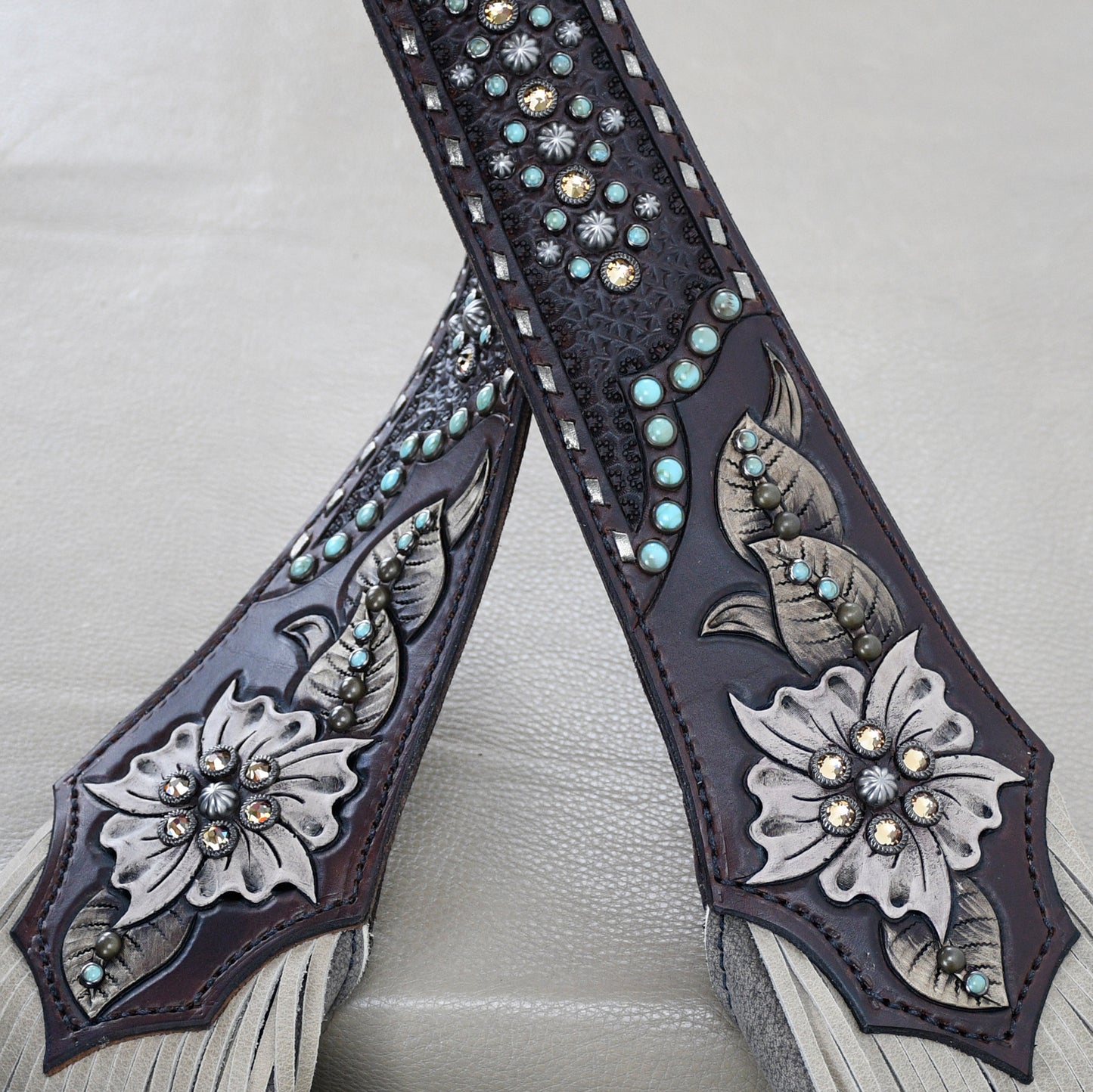 
                  
                    An ornately decorated leather strap with floral patterns and studded embellishments.
                  
                