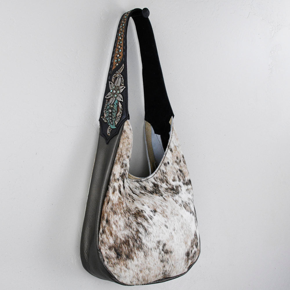 
                  
                    A gray and white Heritage Brand marilyn bag #33 with a decorative strap hanging on a white wall.
                  
                