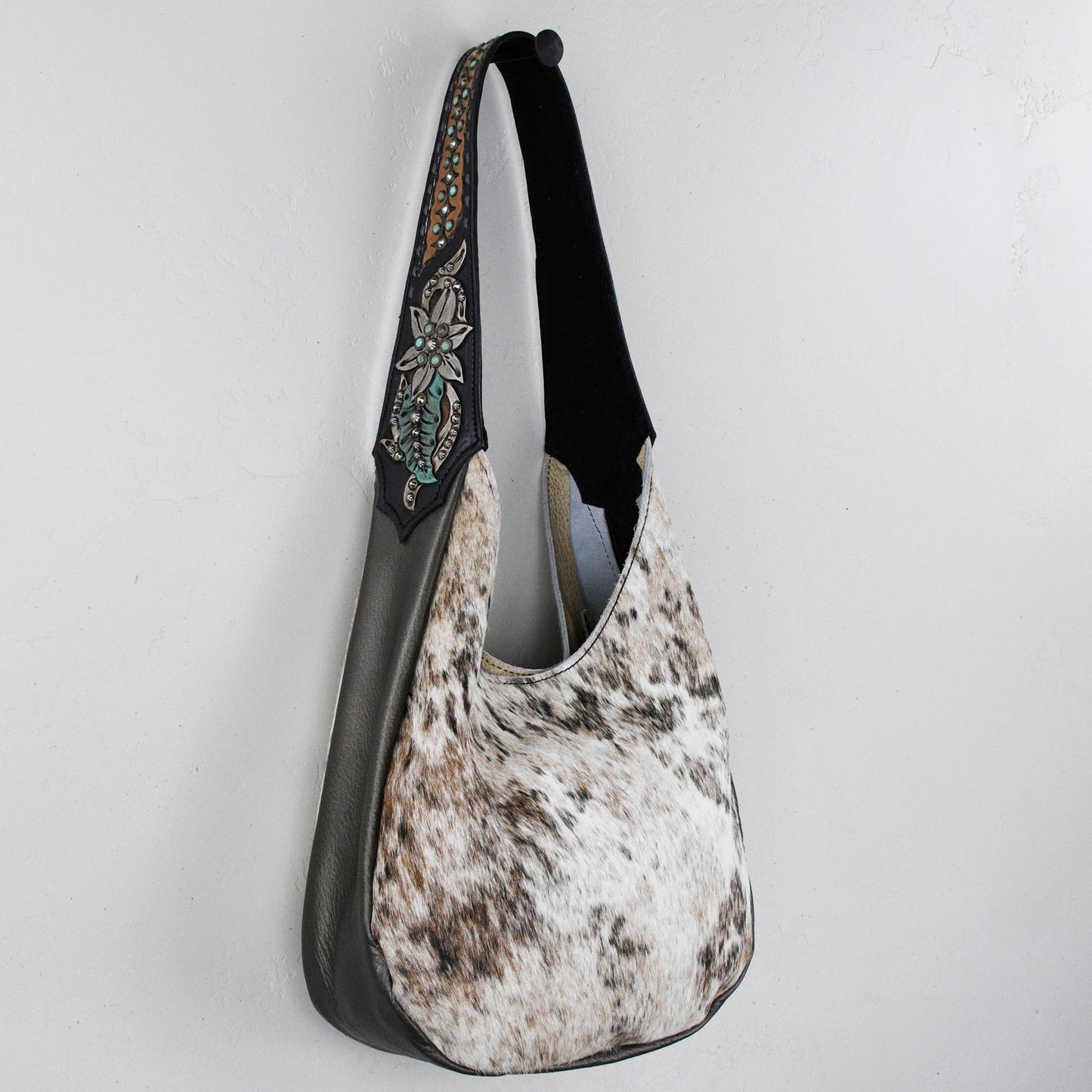
                  
                    A gray and white Heritage Brand marilyn bag #33 with a decorative strap hanging on a white wall.
                  
                