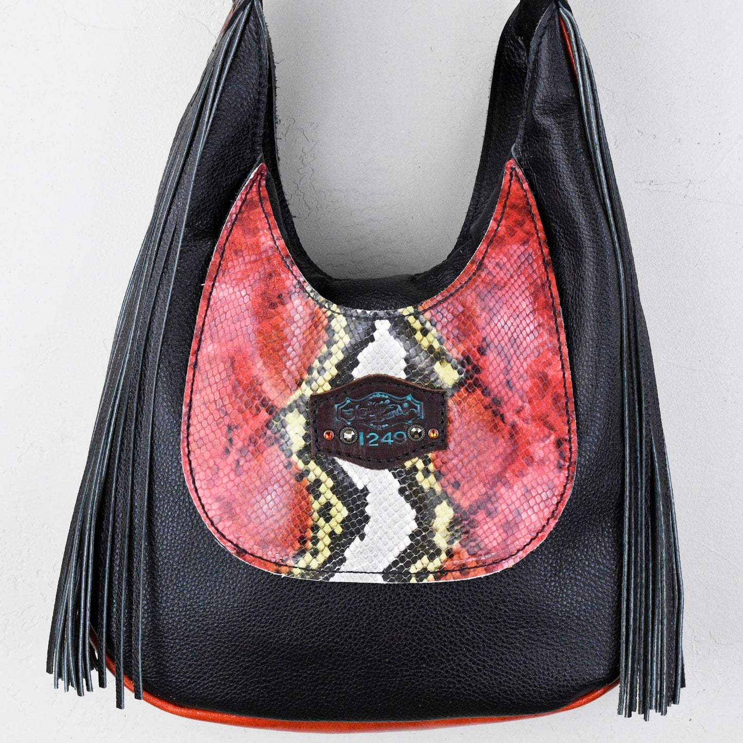 
                  
                    A black and red Heritage Brand marilyn bag #34 with snakeskin texture, fringe details, and a geometric pattern in the center.
                  
                