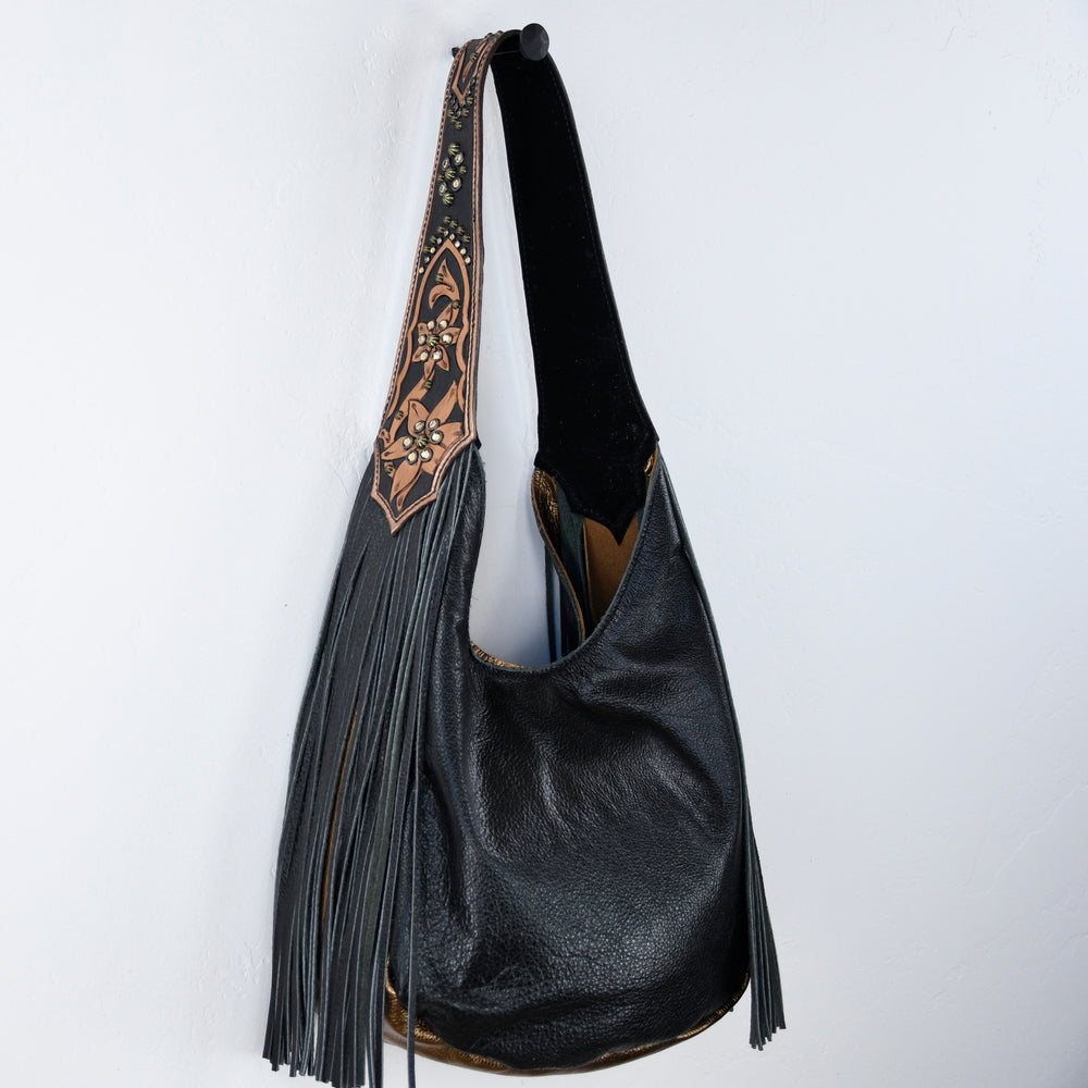 
                  
                    Marilyn bag #650 by Heritage Brand, black leather shoulder bag with tassel details and a patterned strap hanging against a white background.
                  
                