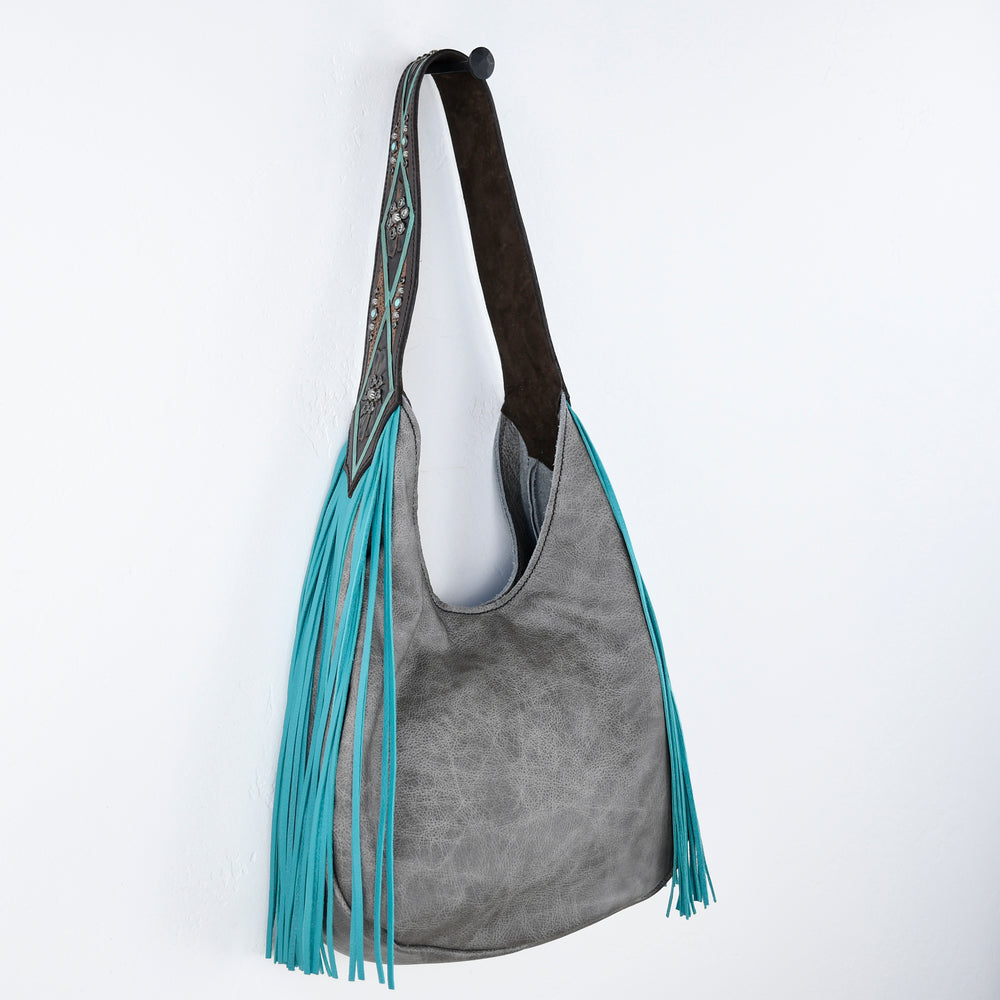 
                  
                    Grey suede marilyn bag #643 with turquoise fringe details hanging against a white background by Heritage Brand.
                  
                