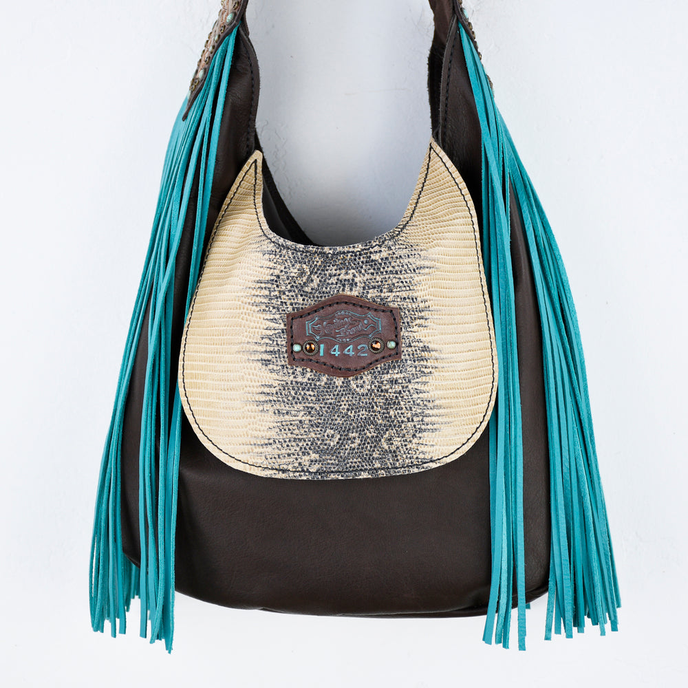 
                  
                    Leather and straw Marilyn bag #658 with turquoise fringes displayed on a mannequin by Heritage Brand.
                  
                