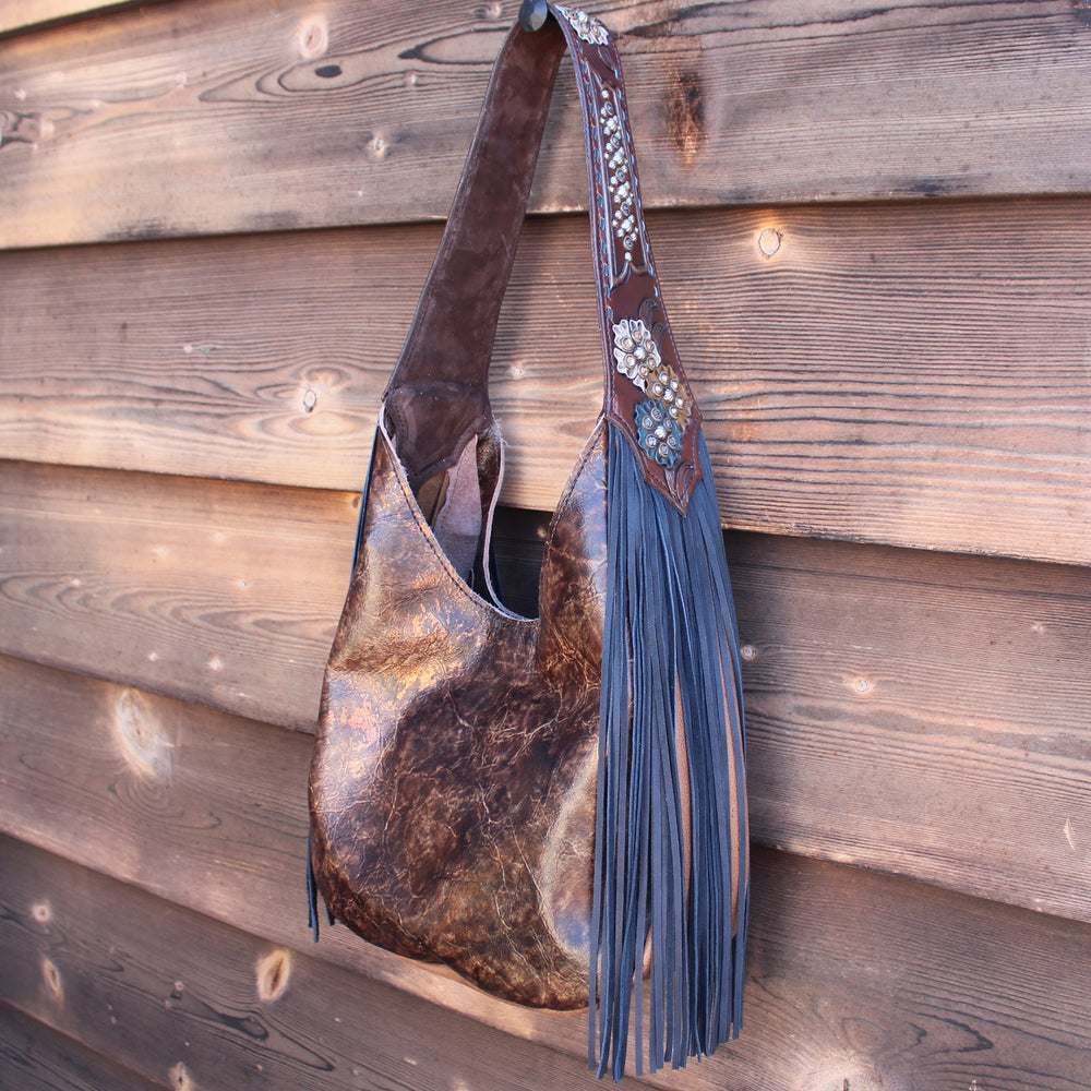 
                  
                    Marilyn bag #985 by Heritage Brand with tassel detail hanging on a wooden wall.
                  
                