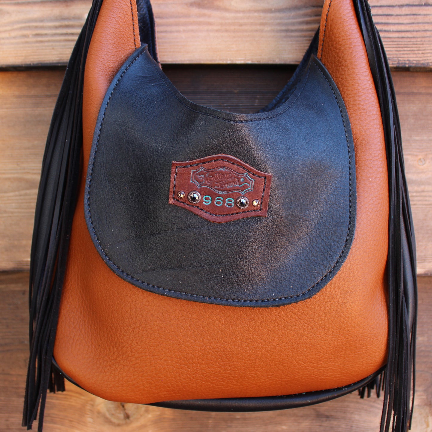 
                  
                    Black and brown leather Marilyn Bag #968 with fringe detail and a Heritage Brand logo patch.
                  
                