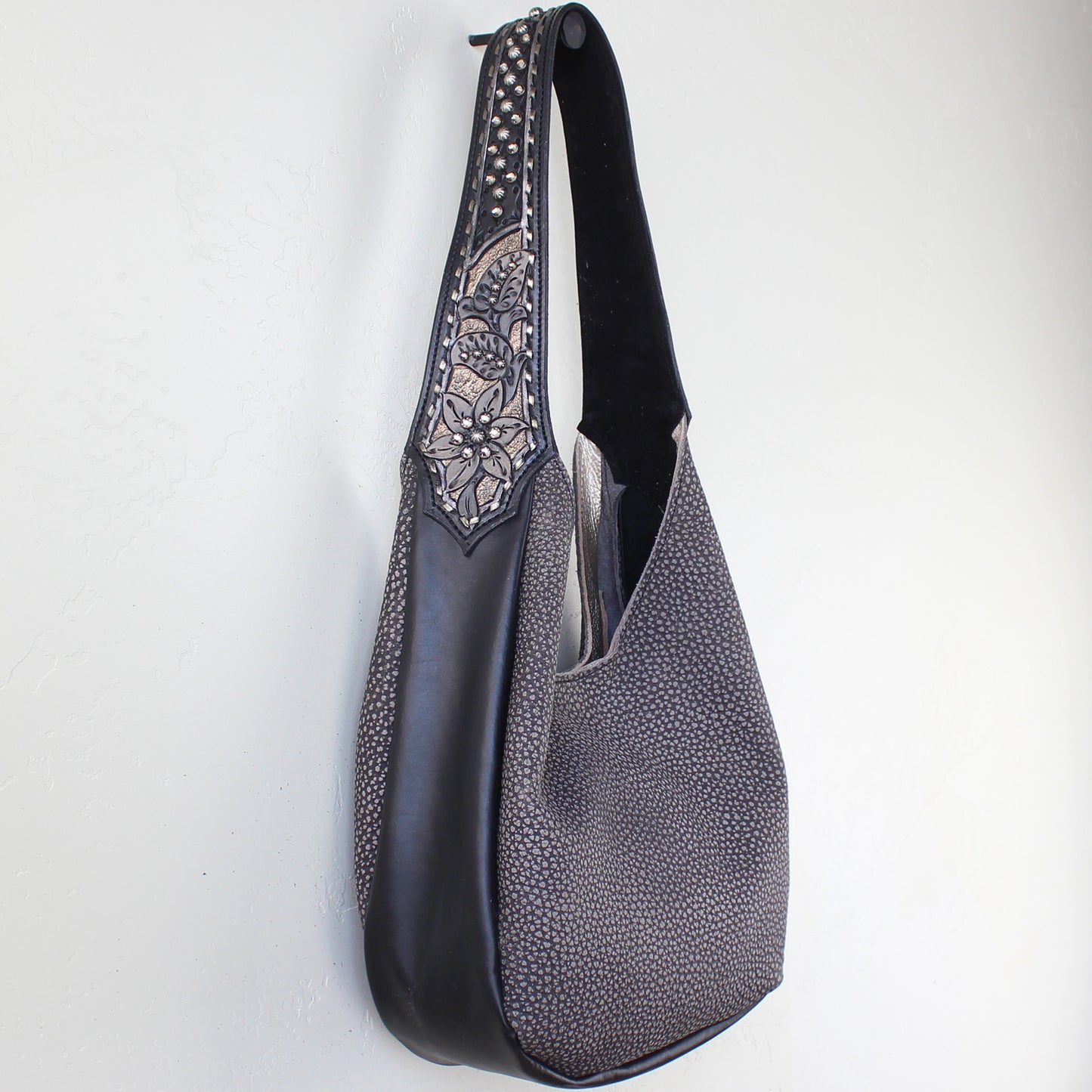 
                  
                    Marilyn bag #1193 by Heritage Brand with studded strap and decorative embroidery hanging against a white wall.
                  
                