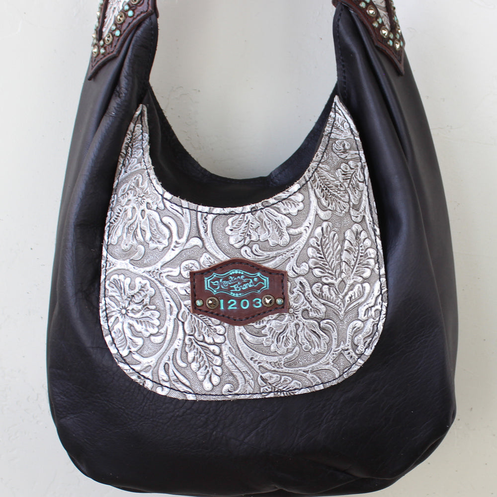 
                  
                    hand-tooled black Marilyn bag #1203 with decorative silver pattern and central label by Heritage Brand.
                  
                